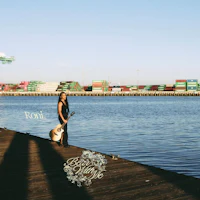 a woman standing on a dock with a guitar