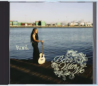 a woman holding an acoustic guitar in front of a body of water