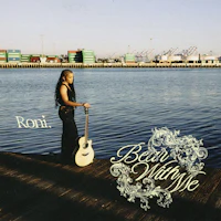 a woman holding an acoustic guitar on a dock